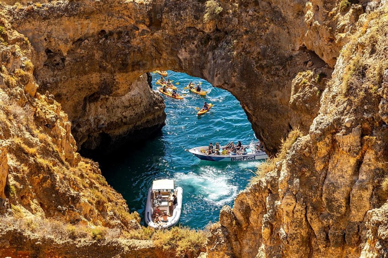 Crowds of excursion boats at the caves and rocky gates of the Ponta da Piedade rocky coast, rugged coastal landscape, right by the centre of Lagos, in the west of the Algarve, Portugal