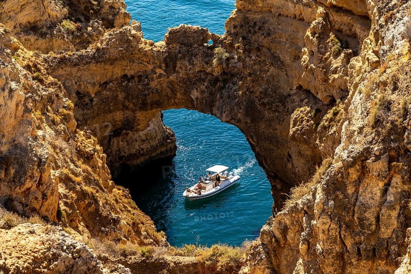 Excursion boats at the caves and rocky gates of the Ponta da Piedade rocky coast, rugged coastal landscape, right by the centre of Lagos, in the west of the Algarve, Portugal