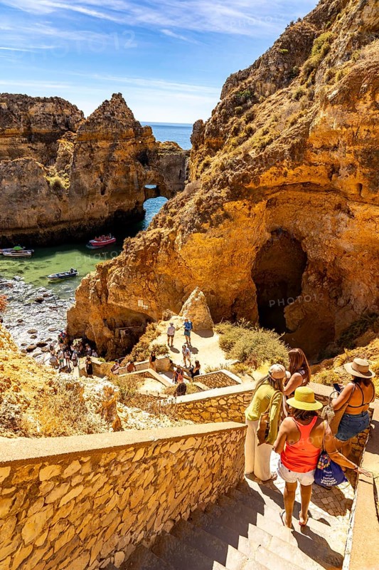 Tourists at the caves and rocky gates of the Ponta da Piedade rocky coast, rugged coastal landscape, right next to the city centre of Lagos, in the west of the Algarve, Portugal