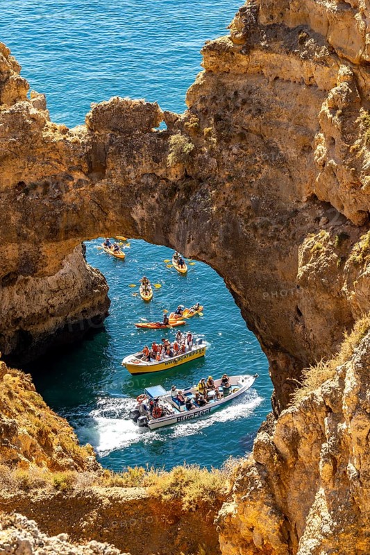 Crowds of excursion boats at the caves and rocky gates of the Ponta da Piedade rocky coast, rugged coastal landscape, right by the centre of Lagos, in the west of the Algarve, Portugal