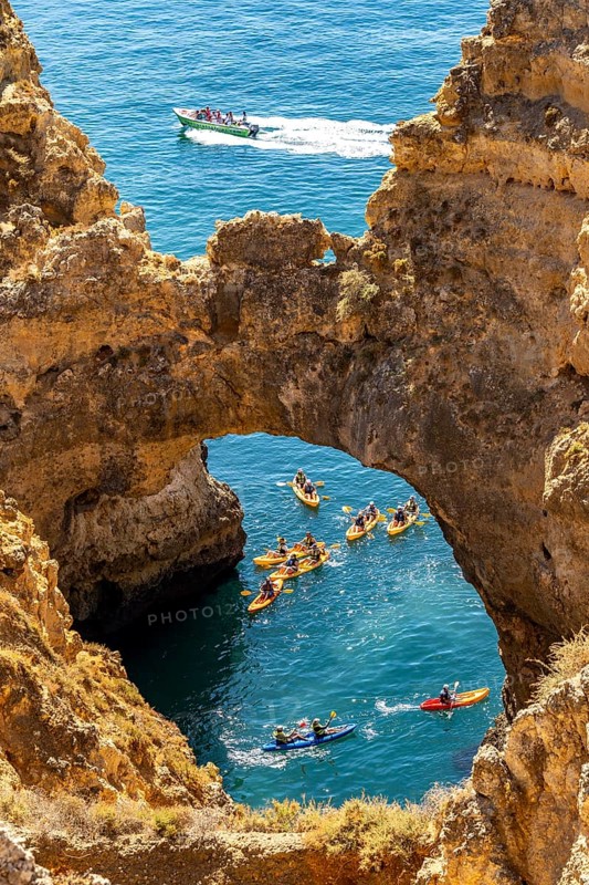 Crowds of excursion boats at the caves and rocky gates of the Ponta da Piedade rocky coast, rugged coastal landscape, right by the centre of Lagos, in the west of the Algarve, Portugal