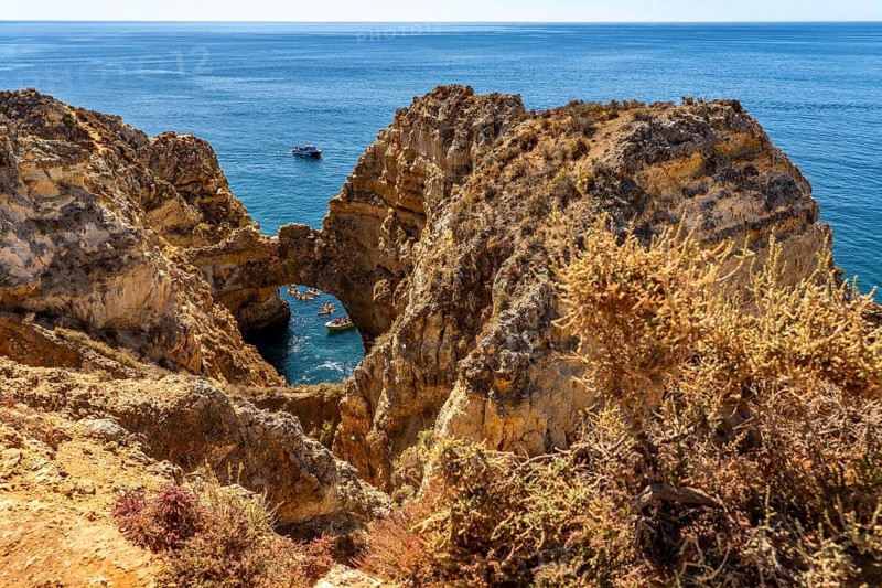 Crowds of excursion boats at the caves and rocky gates of the Ponta da Piedade rocky coast, rugged coastal landscape, right by the centre of Lagos, in the west of the Algarve, Portugal
