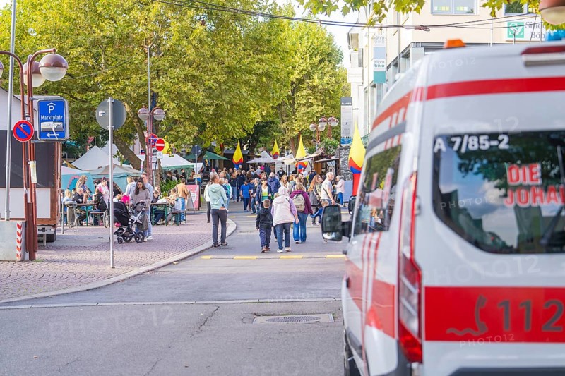 An ambulance parked near a busy market square with a crowd of people, Sindelfingen, Böblingen district, Germany