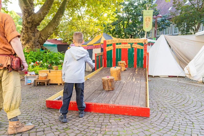 A child plays a medieval wooden game on a market square, Sindelfingen, Böblingen district, Germany
