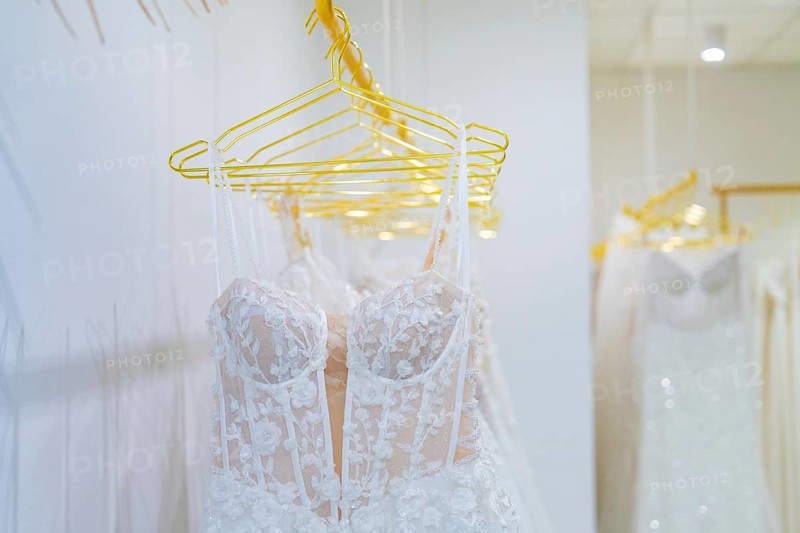 Row of white wedding dresses made of filigree lace presented on yellow hangers, Sindelfingen, Böblingen district, Germany