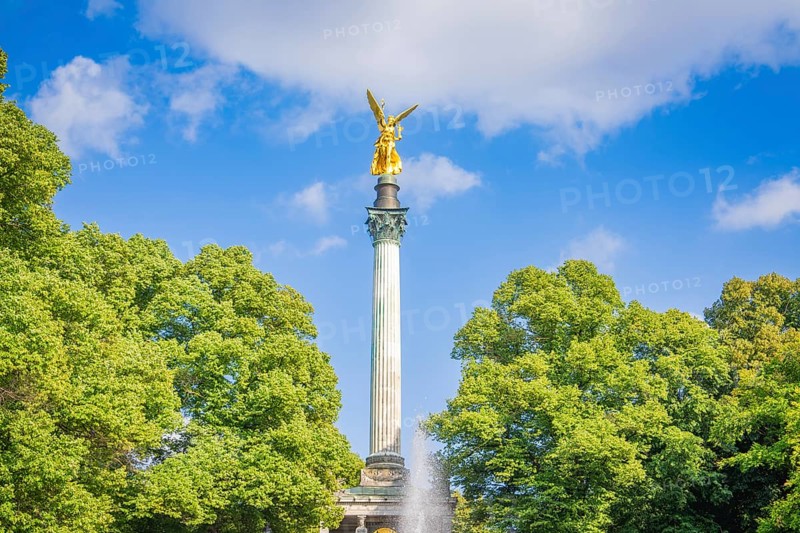 A golden statue rises on a column surrounded by trees, Munich, Germany