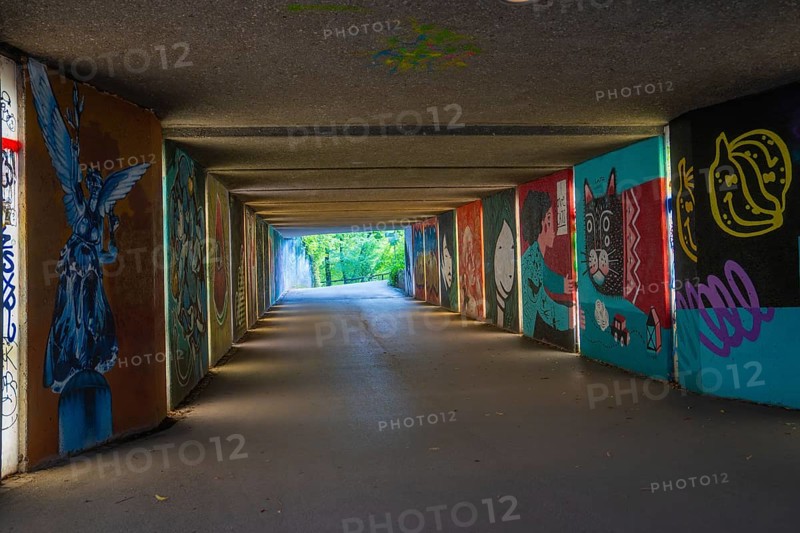A graffiti-covered tunnel leads to a green open-air area, Munich, Germany