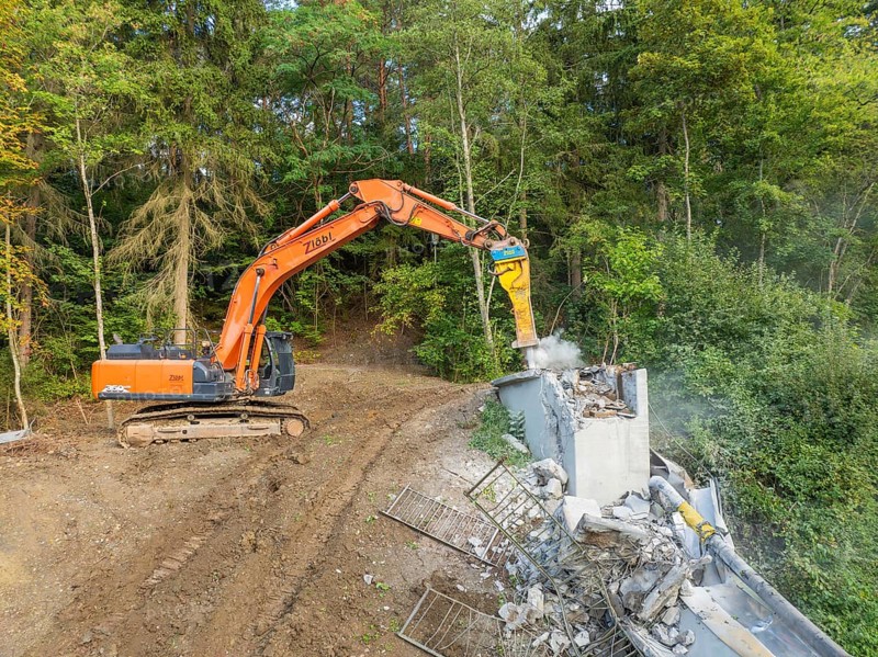 An excavator demolishes a wooden bridge in a wooded area, bridge demolition, Calw, Germany