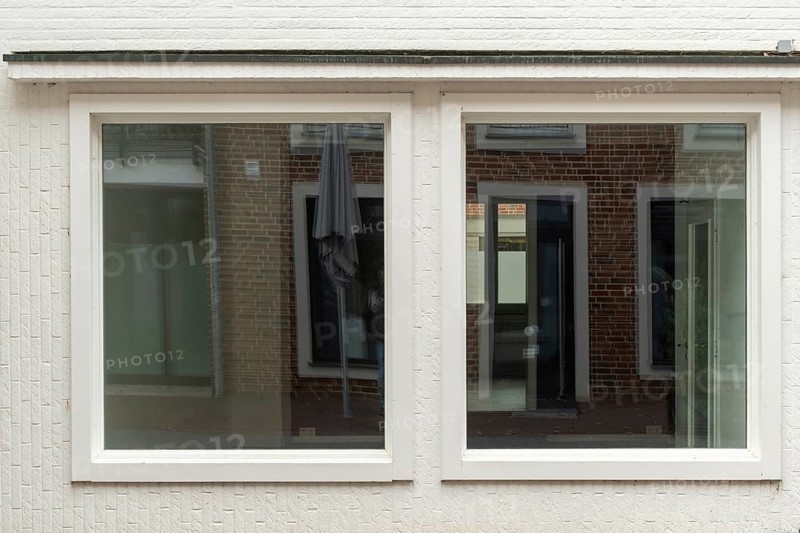 TBorken, NRW, Germany, wo large windows are reflecting a brick building and a parasol on a white wall