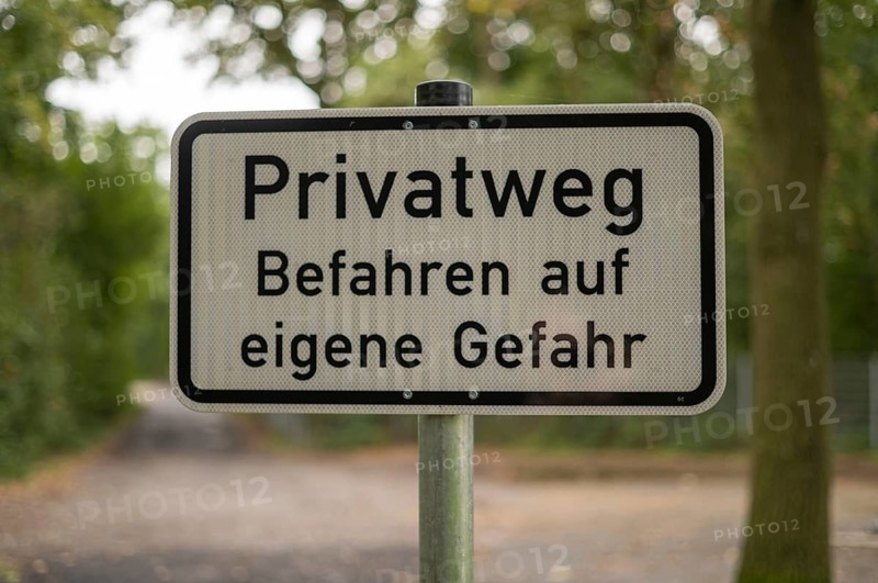 Borken, NRW, Germany, German warning sign privatweg befahren auf eigene gefahr on a pole in a forest path