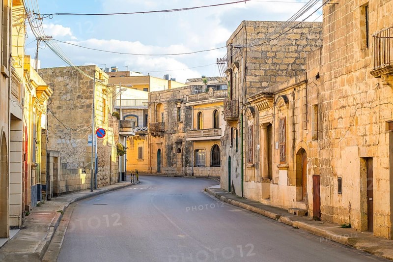 Charming street between limestone building in Nadur, Gozo island, Malta