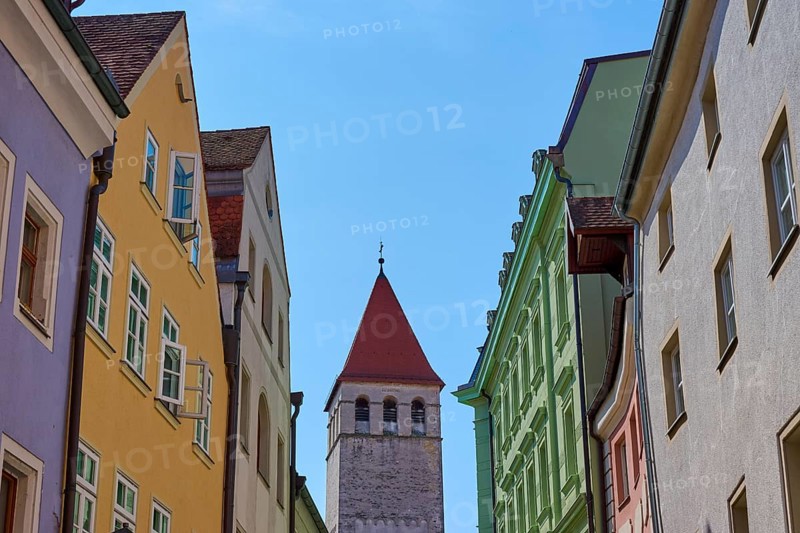 Colourful buildings and church tower along a busy street under a clear sky, Regensburg, Bavaria, Germany