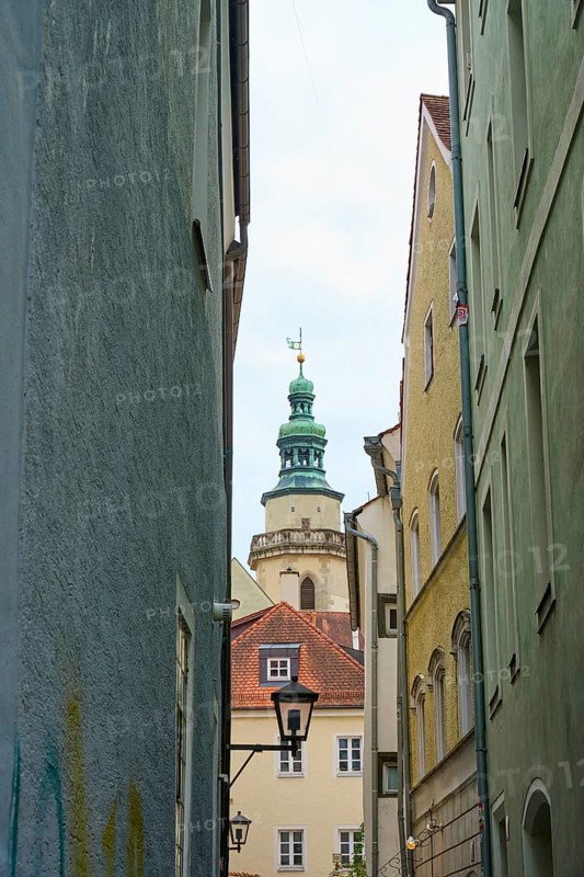 View through a narrow alley to a church tower with surrounding houses, Regensburg, Bavaria, Germany