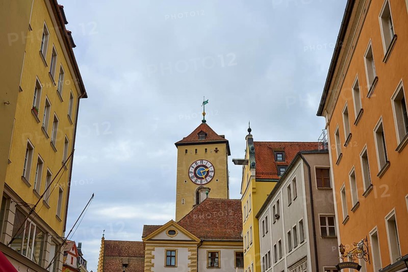 Street scene with a striking tower between historic buildings on a cloudy day, Regensburg, Bavaria, Germany