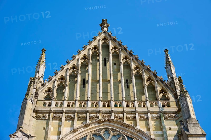Decorated Gothic façade with window and roof spire under a clear sky, St Peter's Cathedral, Regensburg, Bavaria, Germany
