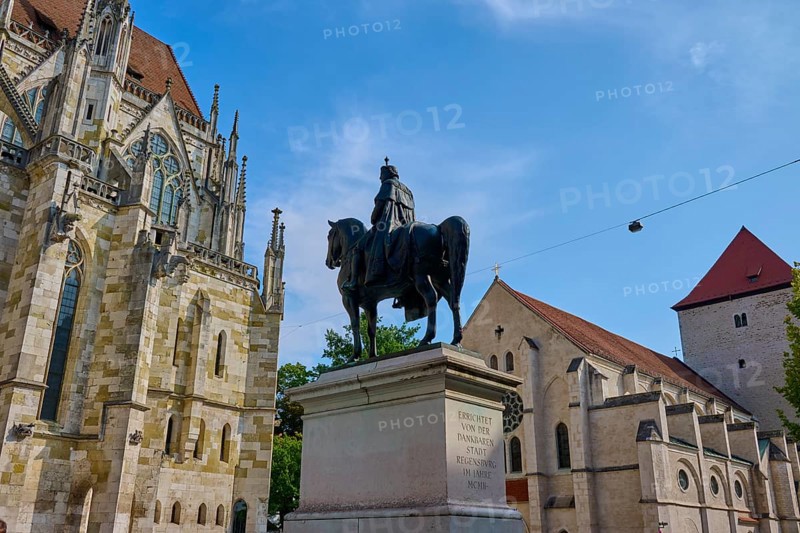 Equestrian statue in front of a historic church under a blue sky, St Peter's Cathedral, Regensburg, Bavaria, Germany