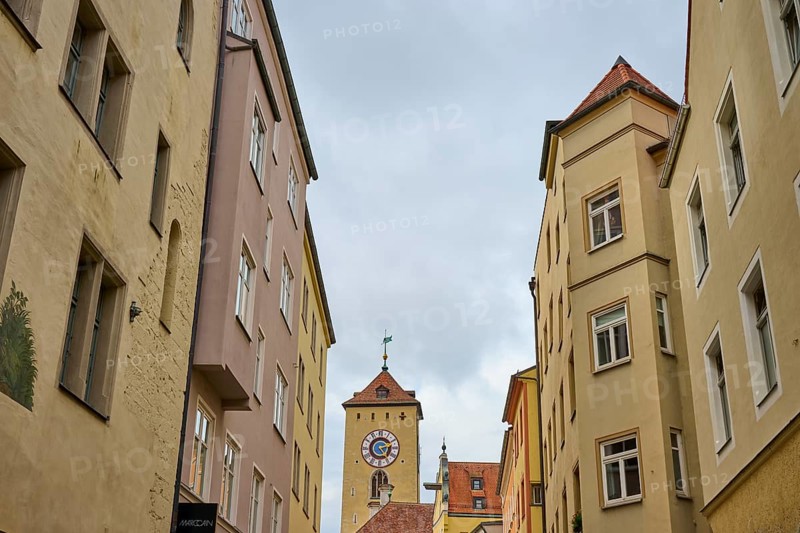 View of a tower through narrow alleys of historic buildings under a grey sky, Regensburg, Bavaria, Germany
