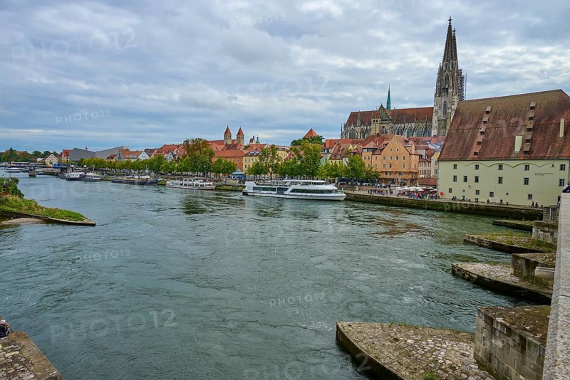 Panorama of a city with cathedral on the riverbank in a cloudy sky, Stone Bridge, Danube, Regensburg, Bavaria, Germany