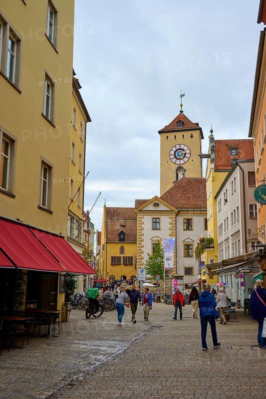 Lively pedestrian zone with a view of the tower, surrounded by historic buildings, Regensburg, Bavaria, Germany