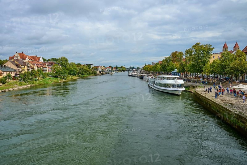 River landscape with boats and houses along the shore under a cloudy sky, Danube, Regensburg, Bavaria, Germany