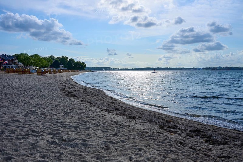Quiet, sun-drenched beach with reflecting water and blue sky with white clouds, Heikendorf, Plön district, Kiel Fjord, Schleswig-Holstein, Germany
