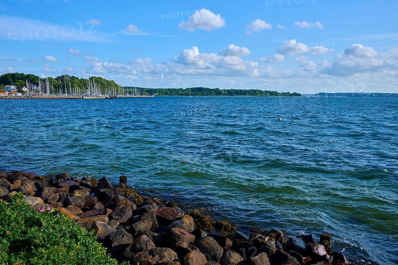 Coastal scene with rocky shoreline and blue sky dotted with clouds, Heikendorf, Plön district, Kiel Fjord, Schleswig-Holstein, Germany