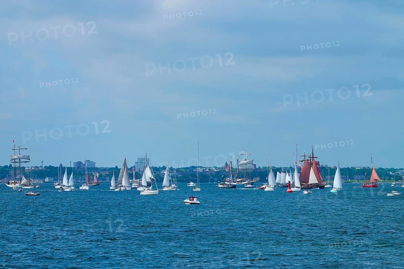 Many sailing boats in front of a city on the blue sea under a partly cloudy sky, Windjammer Parade Kiel 2025, Heikendorf, Kreis Plön, Kieler Förde, Schleswig-Holstein, Germany