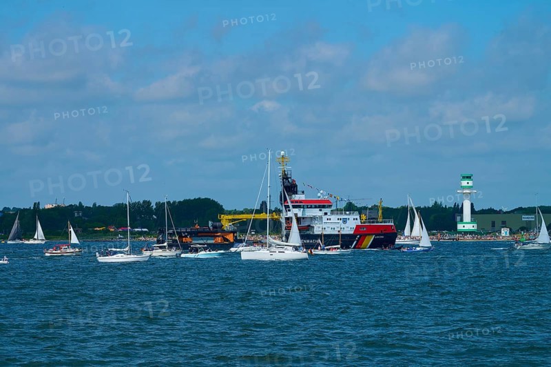 Large ship Arkona Coast Guard and numerous smaller sailing boats in the water in front of a lighthouse Friedrichsort, Windjammer Parade Kiel 2025, district Plön, Kiel Fjord, Schleswig-Holstein, Germany