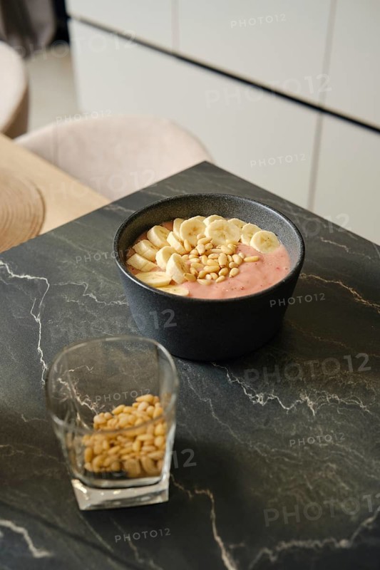 Delicious banana-strawberry smoothie served with pine nuts in a modern kitchen setting