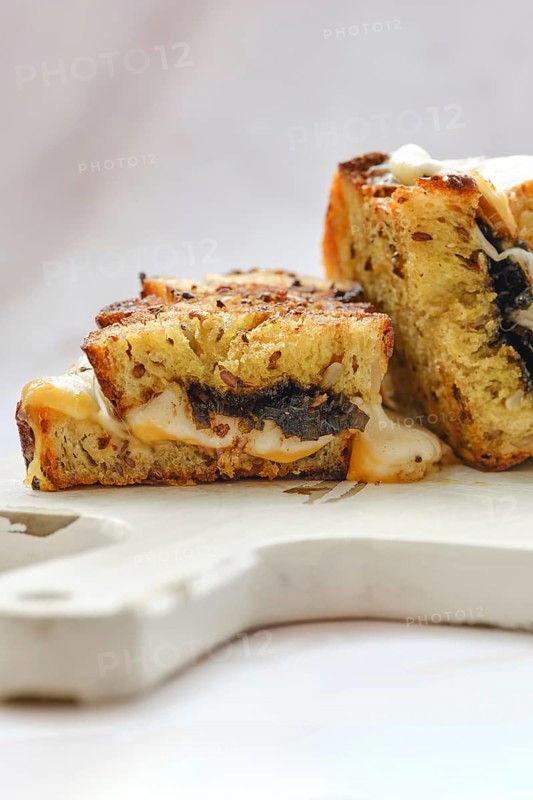Melted cheese oozes from the sides of a perfectly toasted three cheese sandwich, showcasing a golden crust and savory filling