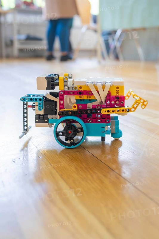 Colourful Lego robot with wheels on a wooden floor demonstrates technical creativity, Youth Research Centre
