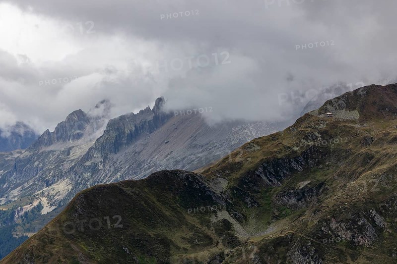 View over the Tremola to the Poncione di Fieud, the peaks of the Bedretto in the clouds, Passo Scimfuss, Airolo, Ticino, Switzerland