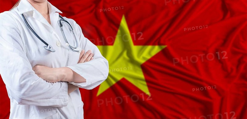 Doctor with crossed arms on Vietnam flag. Vietnam health and care concept. Female doctor on Vietnam flag