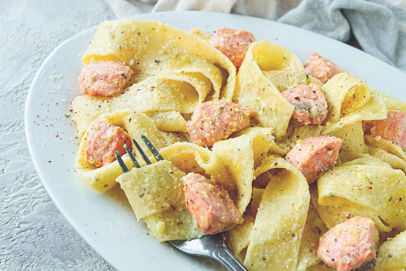 Papardelle pasta, in creamy sauce with salmon, natural light, lifestyle, homemade, on a gray background, no people