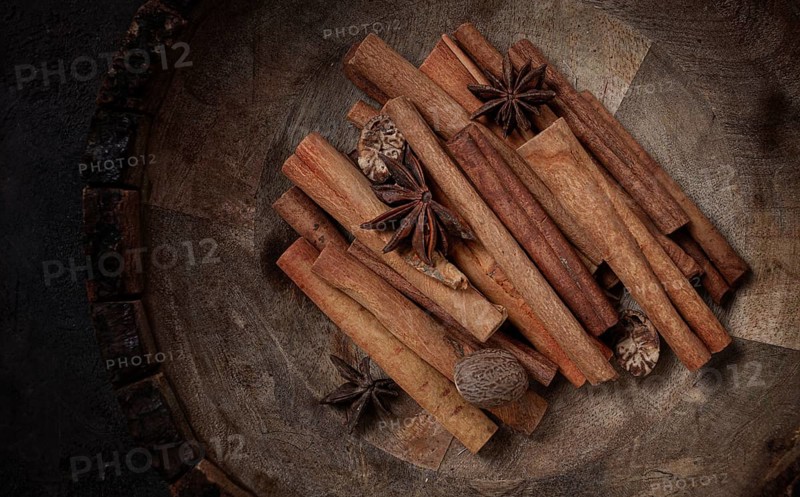 Cinnamon sticks, with nutmeg and anise star, in a wooden plate, top view, no people