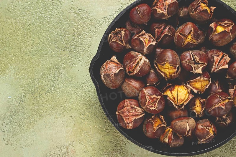 Roasted chestnuts, in an iron pan, wooden table, top view, no people, rustic style