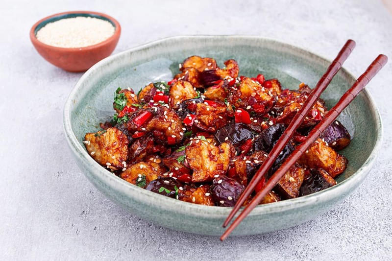 Fried eggplant, Chinese style, in sweet and sour sauce, with pepper and sesame seeds, in a green bowl