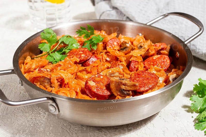 Polish dish bigos, in a stainless steel pan, stewed meat with cabbage, chorizo sausages, mushrooms, homemade, without people