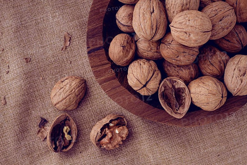 Freshly picked walnuts, in a wooden bowl, on a wooden table, rustic style, no people