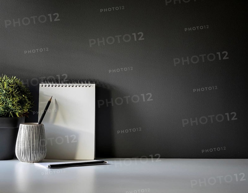 A clean and modern office workspace featuring a pen holder, notebook, and ceramic vase against a dark wall, AI generated