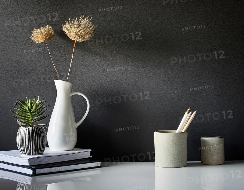 A clean and modern office workspace featuring a pen holder, notebook, and ceramic vase against a dark wall, AI generated