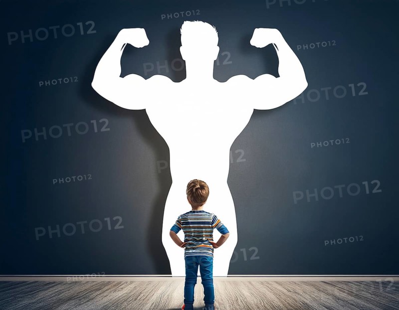A young boy gazes at his shadow, transformed into a superhero, symbolizing imagination, dreams, and personal growth. This powerful image reflects potential, inspiration, and self-confidence in individuals of all ages, AI generated