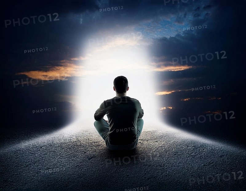 An individual sits in quiet contemplation near the ocean during sunset, surrounded by dramatic clouds, evoking feelings of peace, introspection, and connection to nature, AI generated