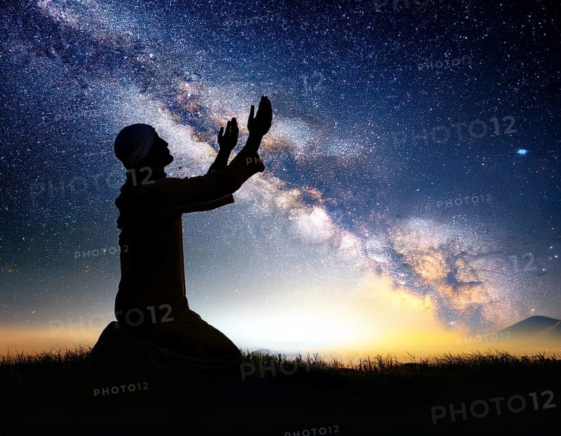 A man kneels in peaceful reflection under the vibrant Milky Way galaxy at sunset in an open natural setting, making prays, AI generated