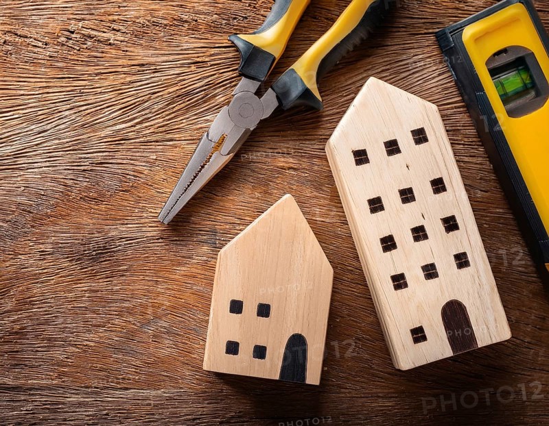 A detailed layout of miniature wooden houses accompanied by various tools on a textured wooden surface, portraying concepts of construction, renovation, craftsmanship, and home improvement, AI generated