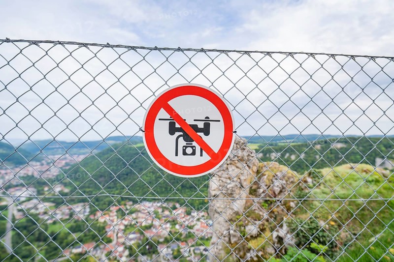 Lattice fence with drone prohibition sign in front of a wide panoramic view over the landscape, Lichtenstein Castle, Lichtenstein, Swabian Alb, Germany