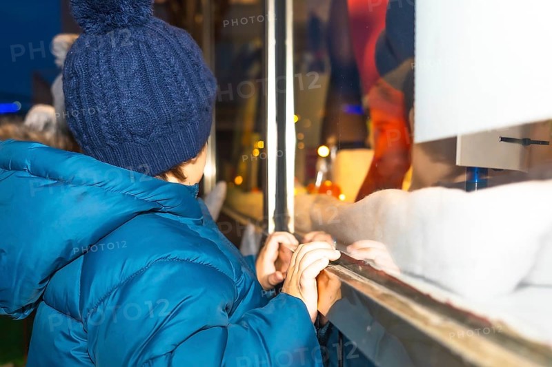 Curious child admiring a festive christmas window display in bayonne, france, during the magical holiday season