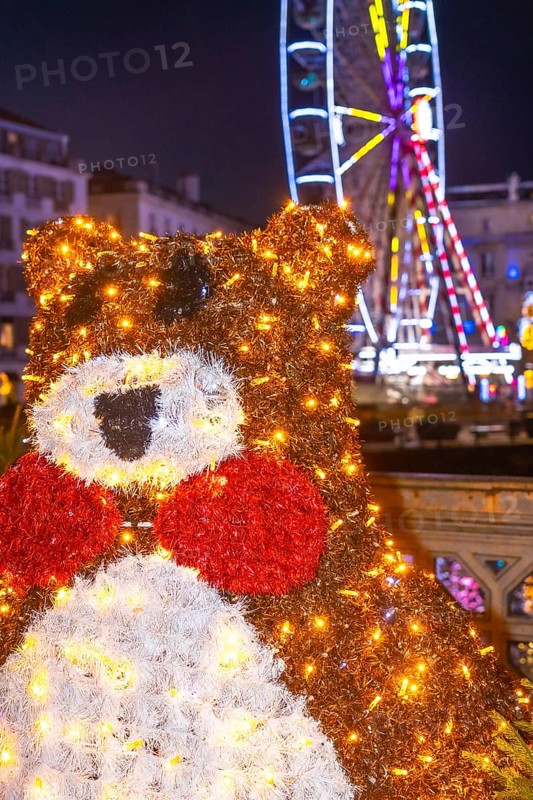 Festive christmas bear decoration shines brightly in bayonne, france, with a ferris wheel adding to the enchanting christmas atmosphere