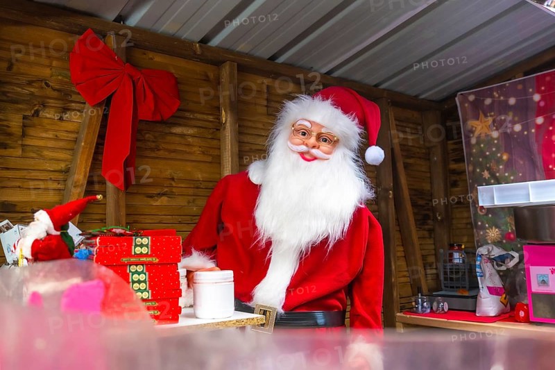 Santa claus impersonator preparing christmas gifts in a wooden kiosk at a christmas market in bayonne, france