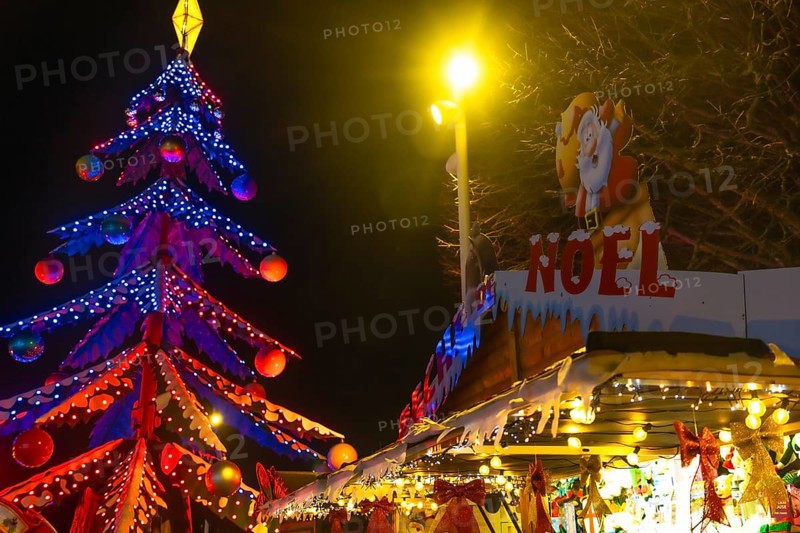 Glowing christmas tree and decorated market stall create festive atmosphere at night in bayonne, france
